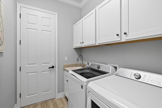 clothes washing area with a sink, cabinet space, light wood finished floors, washer and clothes dryer, and crown molding