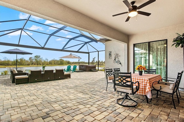 view of patio featuring a hot tub, a ceiling fan, a water view, a lanai, and outdoor dining space