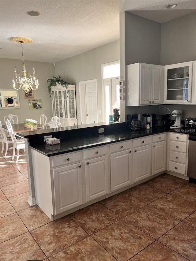 kitchen featuring decorative light fixtures, a chandelier, kitchen peninsula, and white cabinets