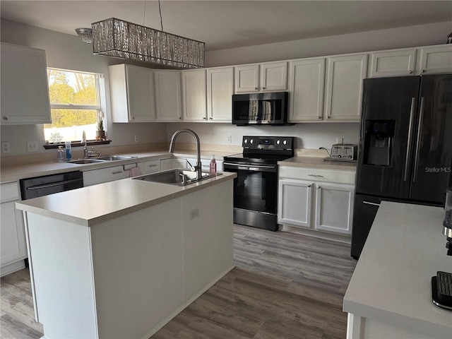 kitchen with white cabinetry, sink, a kitchen island with sink, and black appliances