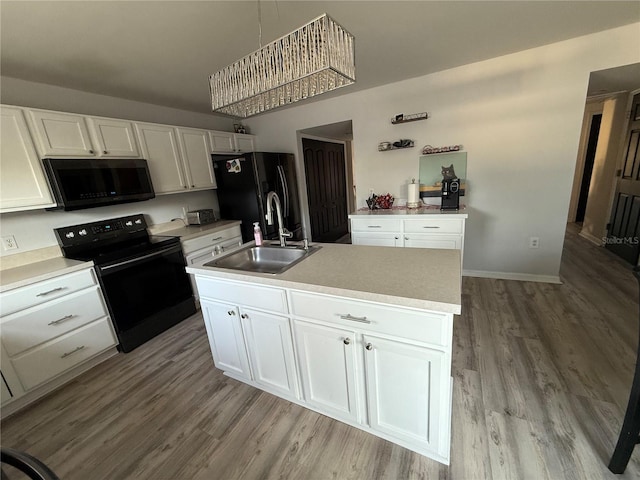 kitchen featuring sink, white cabinetry, hanging light fixtures, black appliances, and a center island with sink