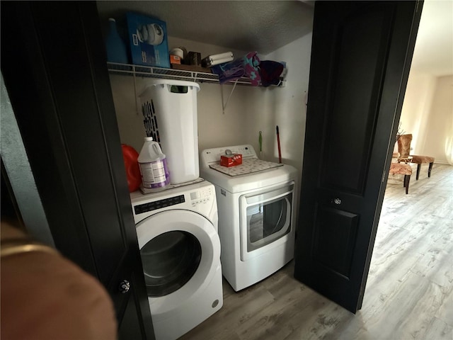 clothes washing area featuring washing machine and dryer and light hardwood / wood-style floors