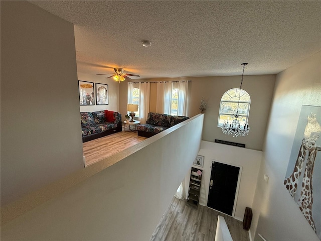 interior space with ceiling fan with notable chandelier, hardwood / wood-style floors, and a textured ceiling