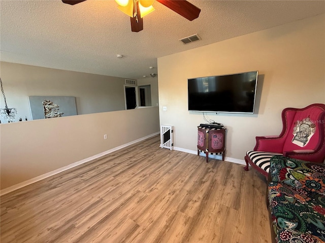 sitting room with ceiling fan, light hardwood / wood-style flooring, and a textured ceiling