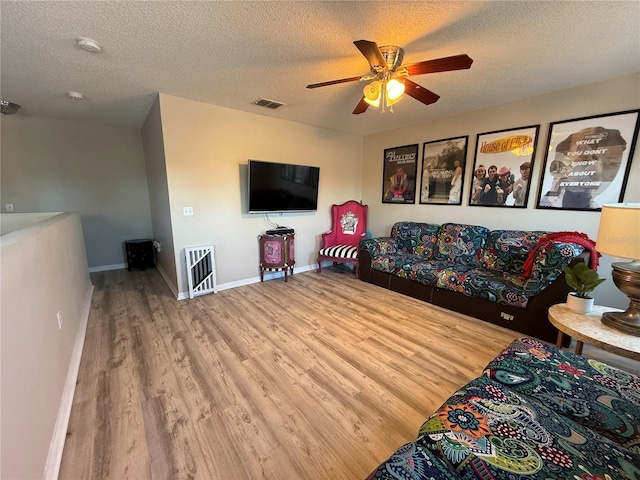 living room with heating unit, ceiling fan, wood-type flooring, and a textured ceiling