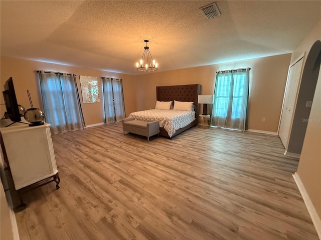 bedroom featuring a chandelier, a textured ceiling, and light wood-type flooring