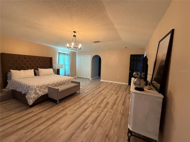 bedroom featuring hardwood / wood-style floors, a notable chandelier, a closet, and a textured ceiling