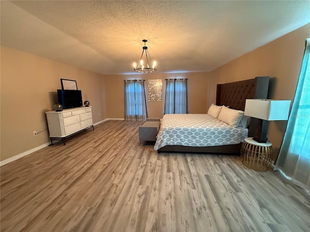 bedroom featuring an inviting chandelier, lofted ceiling, hardwood / wood-style floors, and a textured ceiling