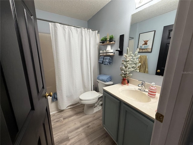 bathroom with wood-type flooring, vanity, walk in shower, toilet, and a textured ceiling