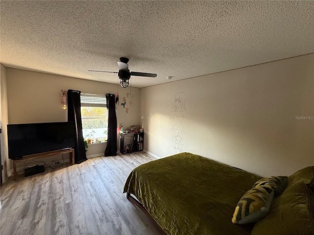 bedroom with ceiling fan, light hardwood / wood-style floors, and a textured ceiling