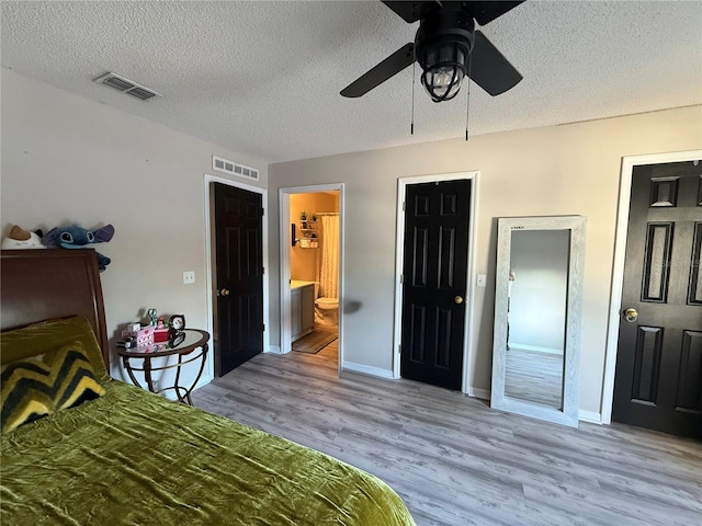 bedroom featuring ceiling fan, a textured ceiling, light wood-type flooring, and ensuite bath