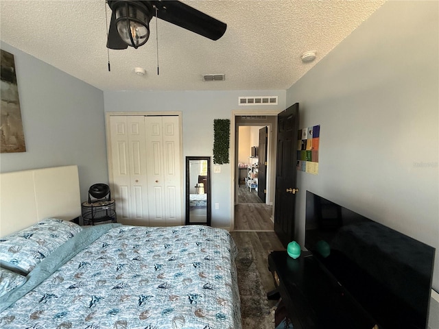 bedroom featuring ceiling fan, a textured ceiling, dark hardwood / wood-style flooring, and a closet