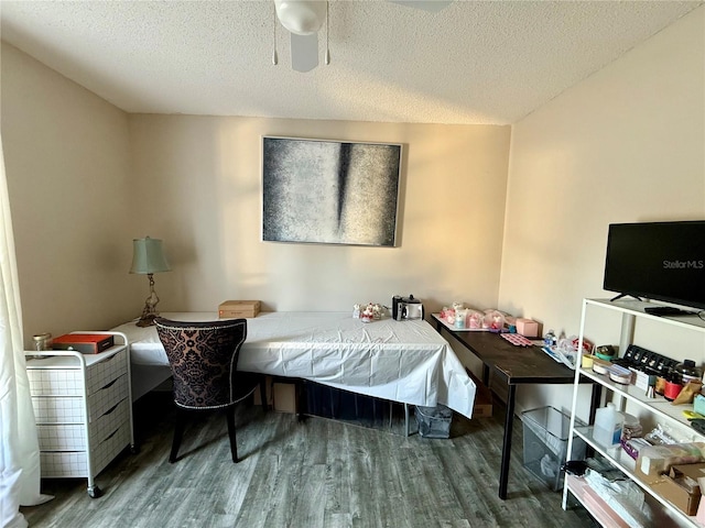 bedroom with ceiling fan, dark hardwood / wood-style floors, and a textured ceiling