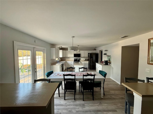 dining area with french doors, sink, and light wood-type flooring