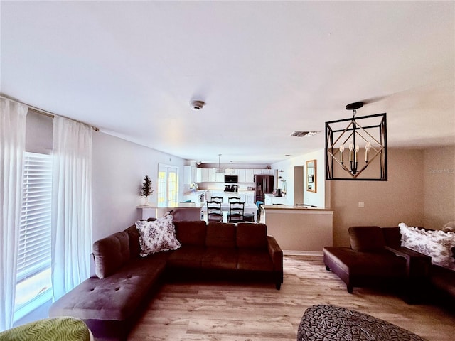 living room with an inviting chandelier and light hardwood / wood-style floors