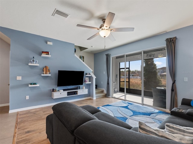 living area with wood finished floors, a ceiling fan, visible vents, and baseboards