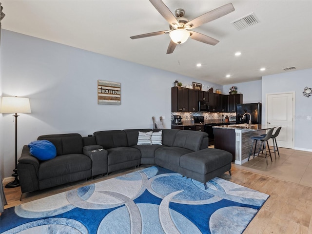 living area with recessed lighting, visible vents, light wood-style floors, and ceiling fan