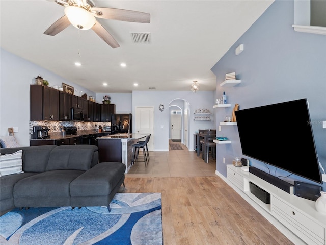 living room featuring visible vents, light wood-style flooring, a ceiling fan, recessed lighting, and arched walkways