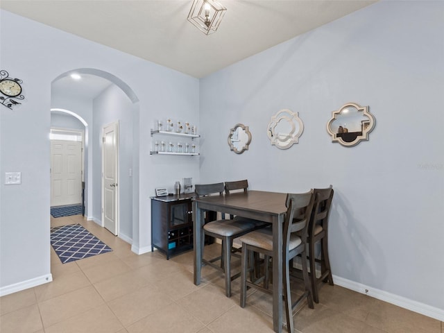 dining room featuring baseboards, arched walkways, and light tile patterned flooring