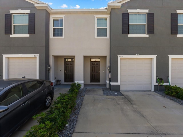 townhome / multi-family property featuring stucco siding, concrete driveway, and a garage