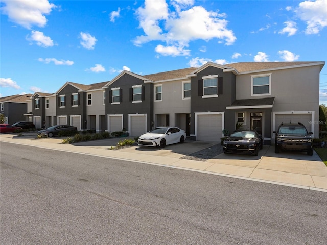 multi unit property featuring a residential view, a garage, driveway, and stucco siding