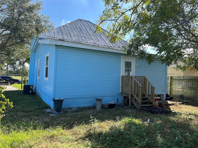 rear view of house featuring cooling unit and a lawn