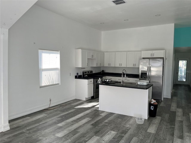 kitchen featuring sink, high vaulted ceiling, a center island with sink, stainless steel appliances, and white cabinets