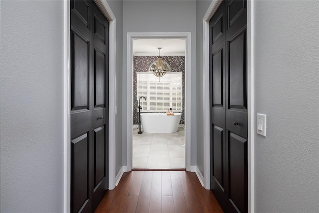 corridor featuring dark hardwood / wood-style flooring and a chandelier