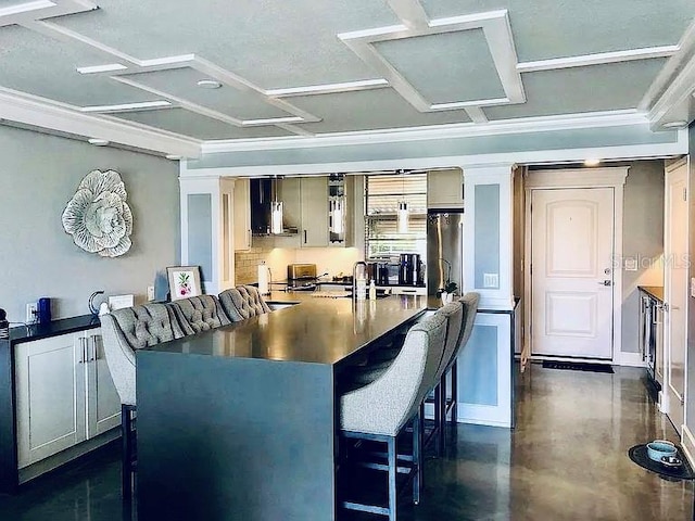 kitchen with sink, stainless steel fridge, a kitchen breakfast bar, decorative backsplash, and coffered ceiling