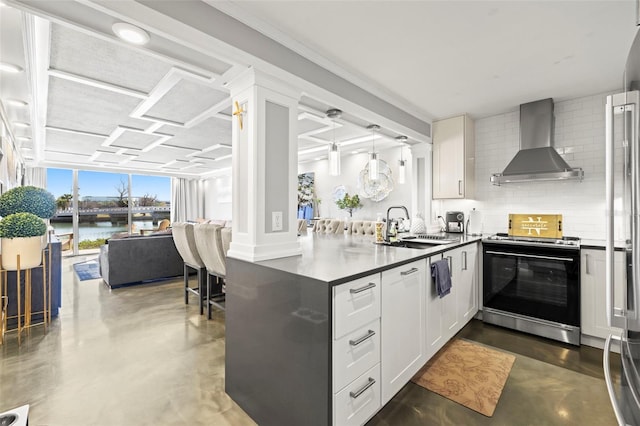 kitchen featuring tasteful backsplash, wall chimney range hood, stainless steel range with electric cooktop, a peninsula, and a sink