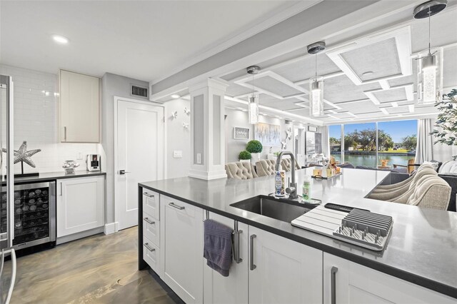 kitchen with visible vents, beverage cooler, a sink, dark countertops, and decorative backsplash