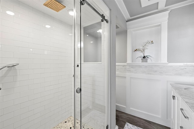 full bath featuring a wainscoted wall, a shower stall, vanity, and a decorative wall