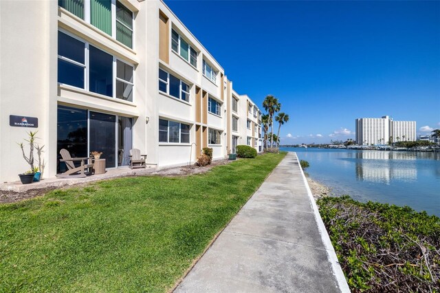 view of property's community with a water view and a lawn