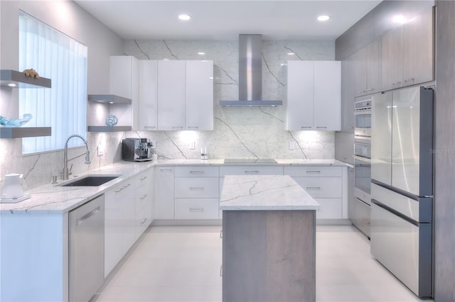 kitchen featuring appliances with stainless steel finishes, sink, white cabinets, a center island, and wall chimney exhaust hood