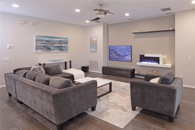 living room with ceiling fan, a fireplace, and dark hardwood / wood-style flooring