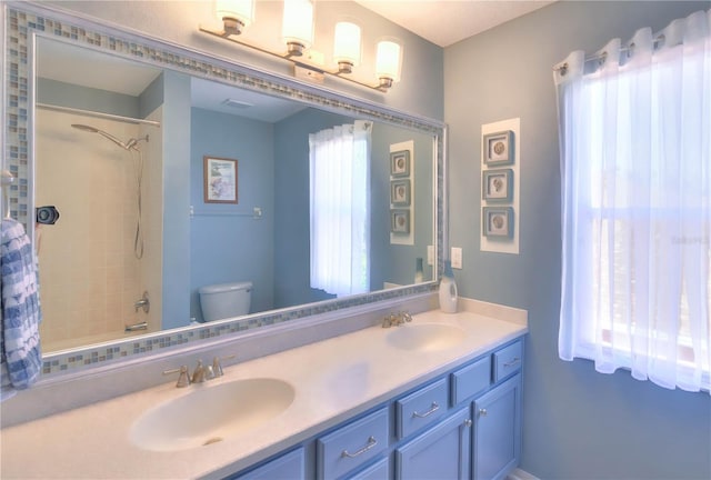 full bathroom with tiled shower / bath combo, vanity, and toilet