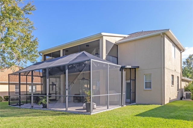 back of property with a patio, a lanai, central AC unit, and a lawn