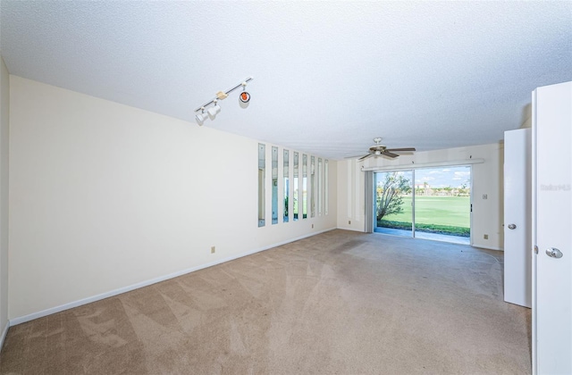 carpeted spare room with track lighting and a textured ceiling