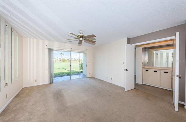 spare room with ceiling fan, light carpet, and a textured ceiling