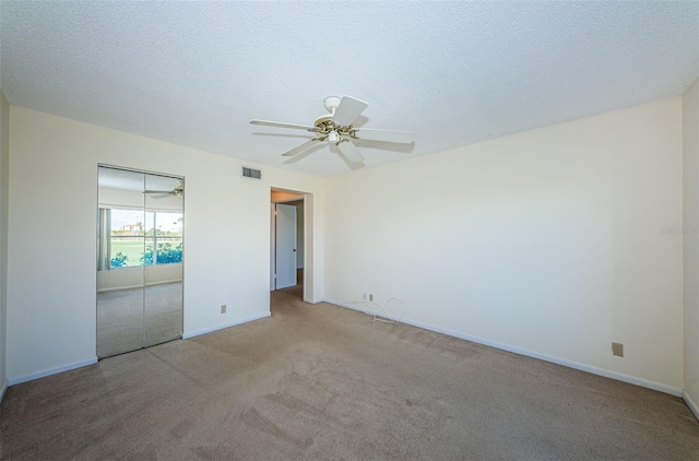 unfurnished bedroom featuring ceiling fan, light colored carpet, a closet, and a textured ceiling