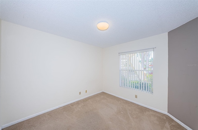 empty room with light colored carpet and a textured ceiling