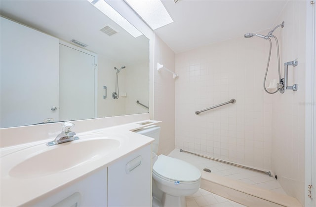 bathroom with vanity, toilet, and a tile shower