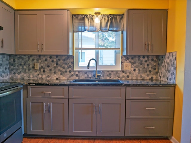 kitchen with stainless steel electric range oven, sink, dark stone countertops, and gray cabinetry