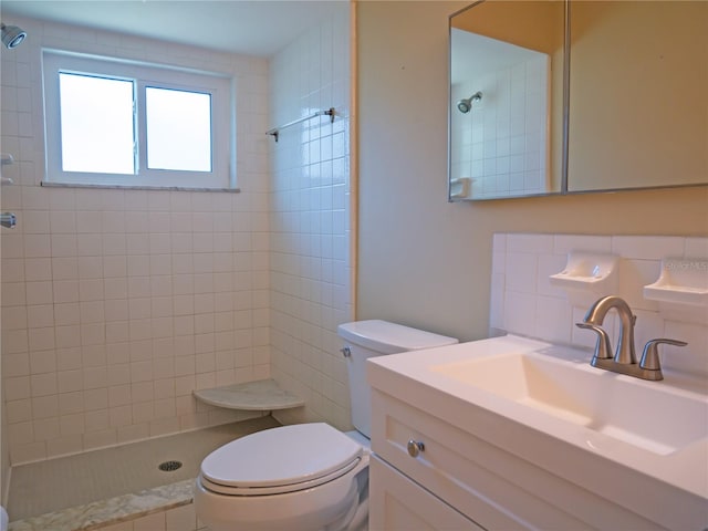 bathroom with a tile shower, backsplash, vanity, and toilet