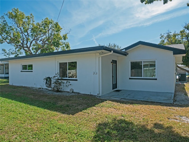 rear view of house with a patio, cooling unit, and a lawn