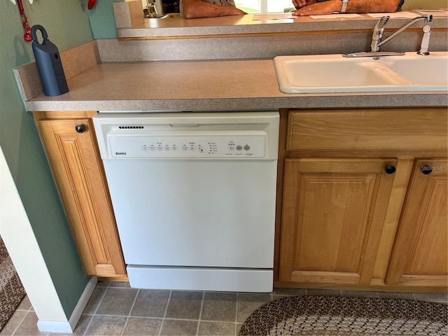 kitchen featuring white dishwasher, sink, and dark tile patterned flooring