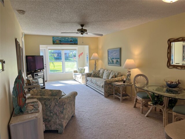 carpeted living room with ceiling fan and a textured ceiling