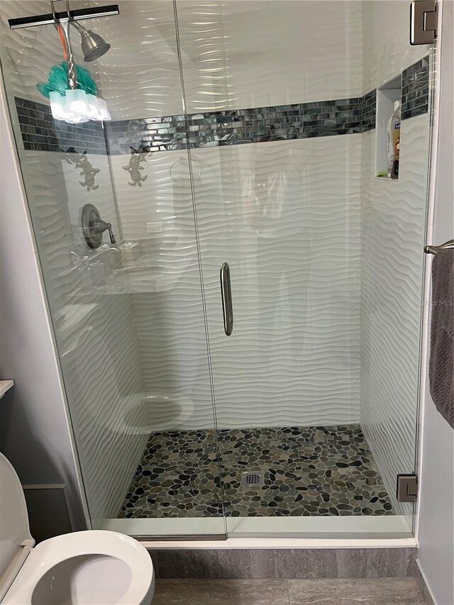 bathroom featuring toilet and a shower with door