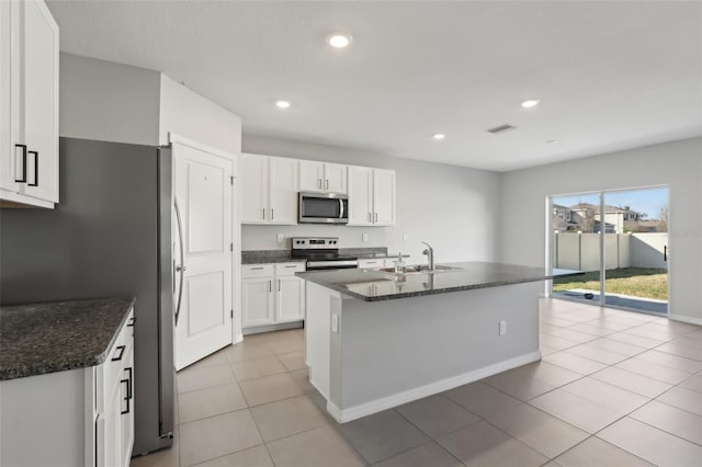 kitchen with sink, a center island with sink, appliances with stainless steel finishes, dark stone counters, and white cabinets