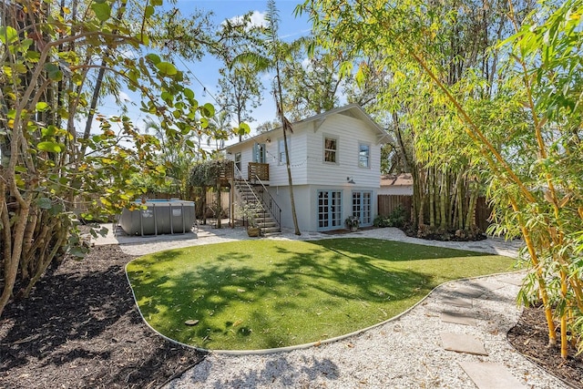 back of house with french doors, a hot tub, a patio area, and a lawn